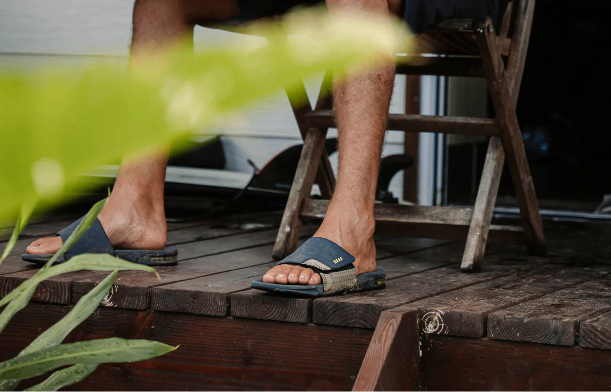 Man sitting on a tropical deck wearing the Fanning Slide.