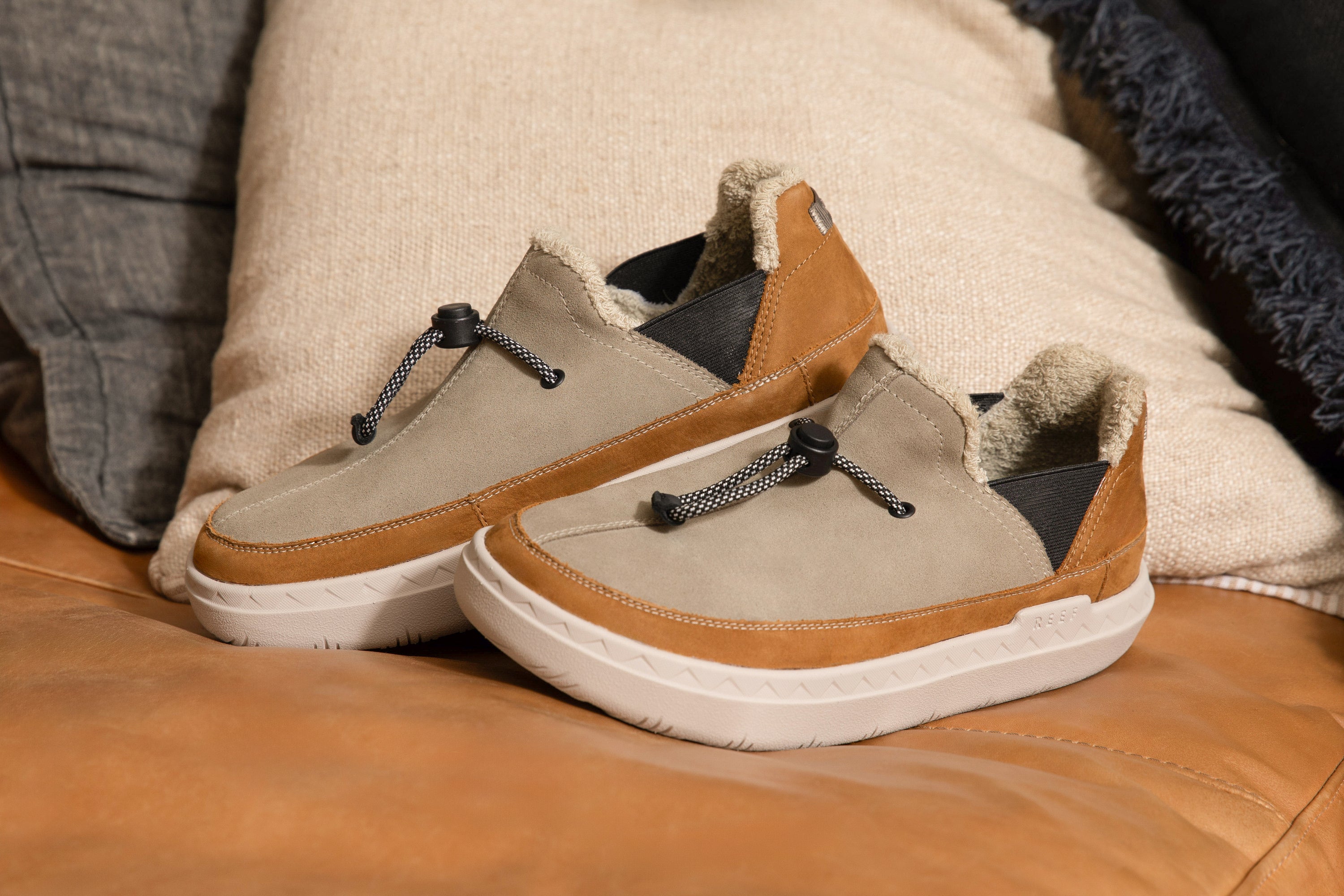 Mid 30s male wearing the Homey Slippers next to a fireplace