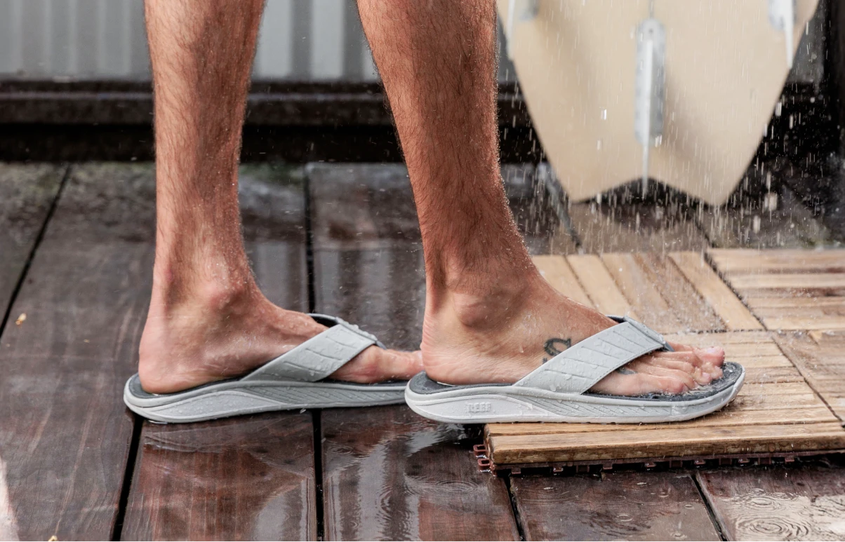 Close up of a man using an outdoor shower wearing the Deckhand sandal.