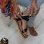 Woman adjusting black Cushion Rem Hi sandal on left foot, showing top and side with soft cushioning and arch support.