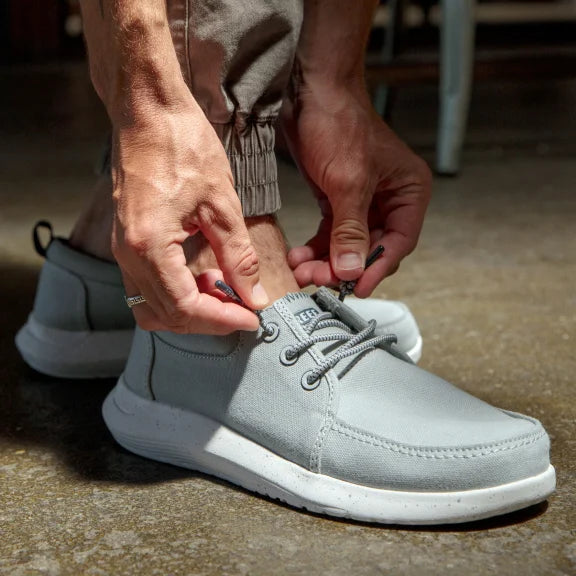 Man tying shoe laces wearing the SWELLsole Cutback shoes.