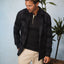 Man wearing a black and gray Reggie Flannel Shirt over a black henley, styled casually with beige pants indoors.