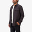 Man wearing a dark Raymond Ls Shirt with front chest pockets, styled open over a white tee, showing comfort-focused casual wear.