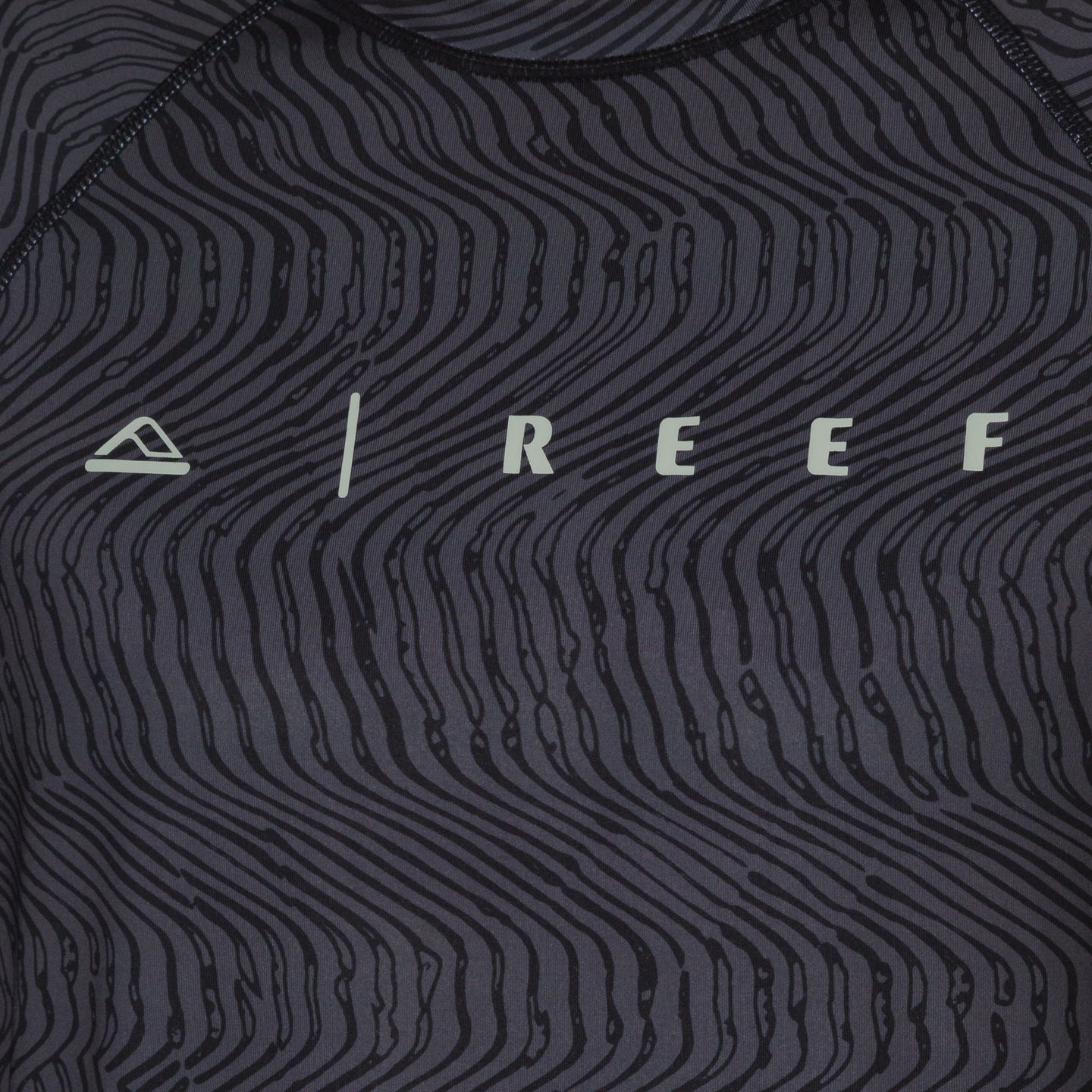 Close-up of the front chest area of the men's Dune Performance Shirt with a black wavy line pattern and REEF logo.