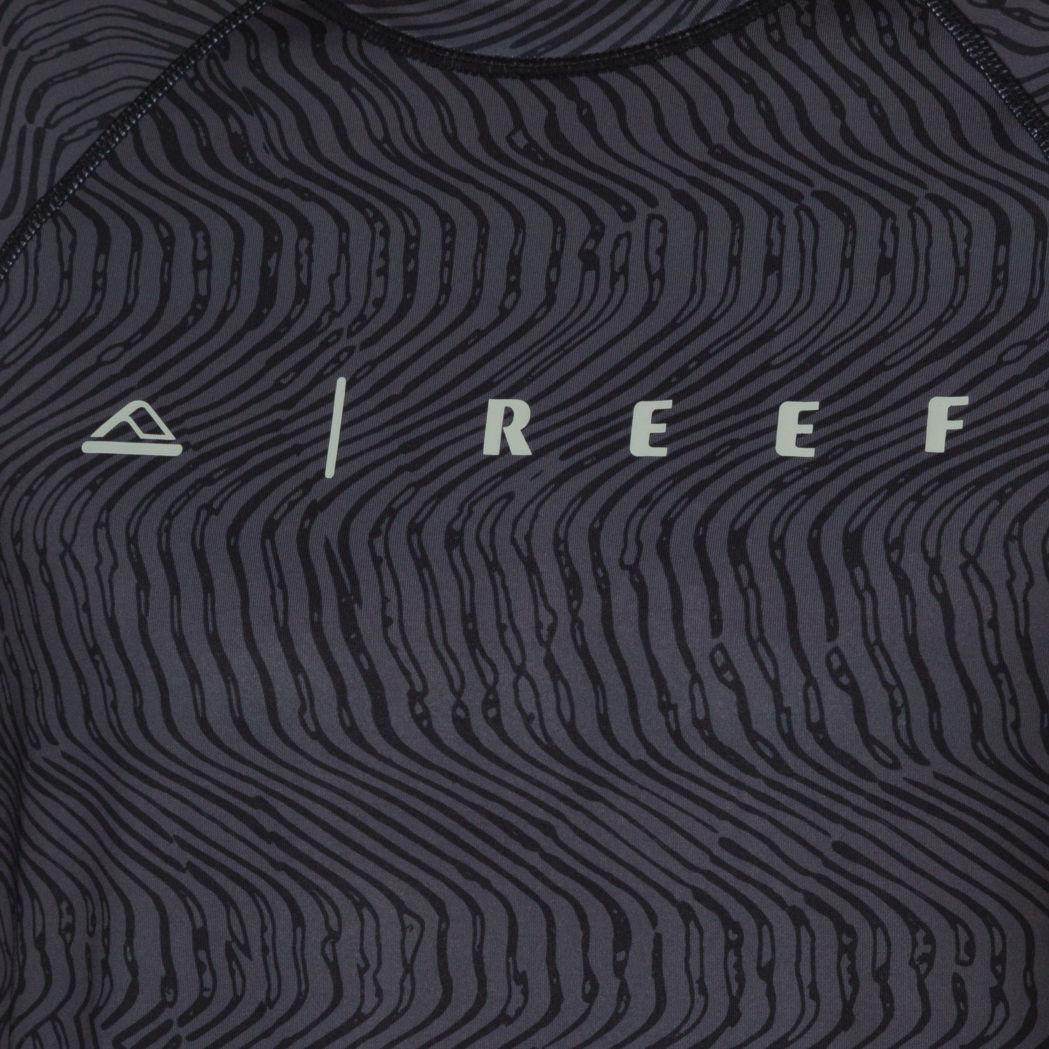 Close-up of the front chest area of the men's Dune Performance Shirt with a black wavy line pattern and REEF logo.