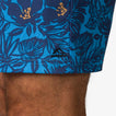 Close-up of the lower hem of the Felix Boardshort in blue with tropical print worn on a man's leg, showcasing comfort and style.
