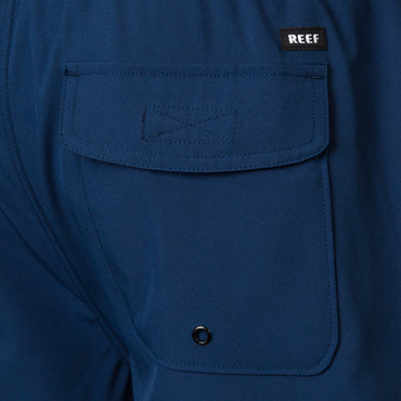 Close-up of the back pocket on the Garland Hybrid Short in navy blue, highlighting the REEF logo and durable stitching.