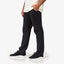 Men wearing black Carrick Stretch Pant facing left, paired with black REEF sneakers featuring anatomical arch support.