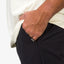 Close-up of a man's hand in the front pocket of black Carrick Stretch Pant showcasing comfort and surf-inspired design.