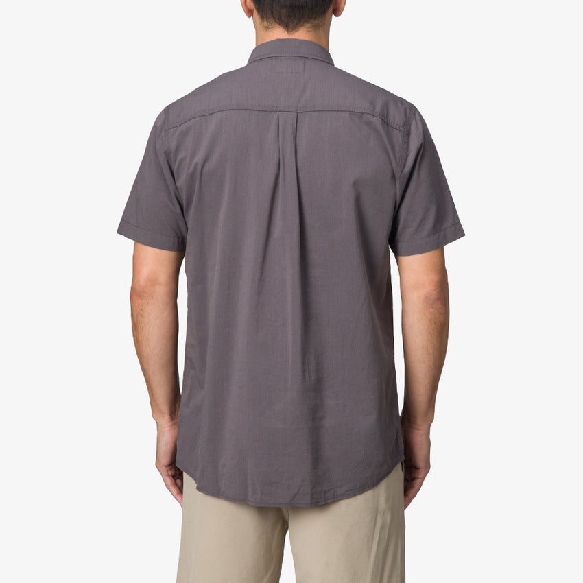 Back view of a man wearing a grey Collins Ss Wvn Shirt with short sleeves, casual fit for beach and active lifestyle.