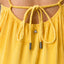 Close-up of back detail on women's Plisse Dress with braided straps and pleated yellow fabric, surf-inspired comfort.
