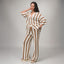 Woman wearing Mika Sweater Pant in brown and white stripes, standing with one hand behind head, front view, barefoot.
