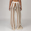 Back view of woman wearing Mika Sweater Pant with brown and white stripes, paired with beige sandals facing right.