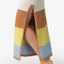 Close-up of the Gia Maxi Dress side slit showing striped knit fabric in neutral, brown, yellow, and blue tones on woman's leg.