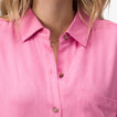Close-up of the collar and chest pocket of the pink Ollie Shirt Dress showing textured fabric and wooden buttons.