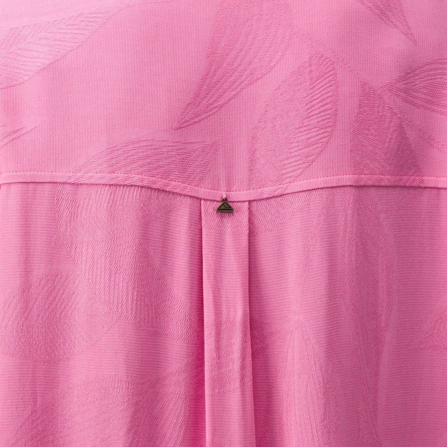 Close-up of pink Ollie Shirt Dress fabric showing textured leaf pattern and small metal logo detail on the back panel.