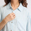 Close-up of a woman adjusting the collar of the Ollie Striped Shirt Dress with light blue and white stripes.