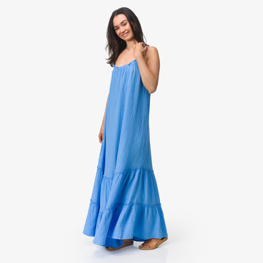 Woman wearing blue Lainey Maxi Dress standing facing forward with relaxed smile, showcasing lightweight beach apparel.