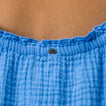 Close-up of the top back of the Lainey Maxi Dress in soft blue fabric with a small metal logo detail.