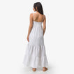 Woman wearing a white Yuni Maxi Dress facing backward, showing the dress's tiered design and adjustable straps.