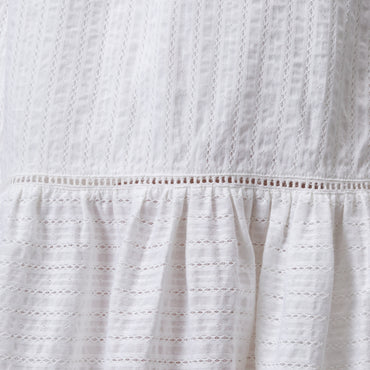 Close-up of white Yuni Maxi Dress fabric showing textured eyelet and delicate stitching details.