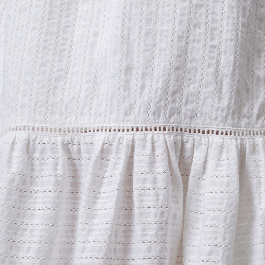 Close-up of white Yuni Maxi Dress fabric showing textured eyelet and delicate stitching details.