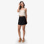 Woman wearing Tori Linen Wrap Skort in black, standing with brown platform sandals facing forward, beach-inspired comfort apparel