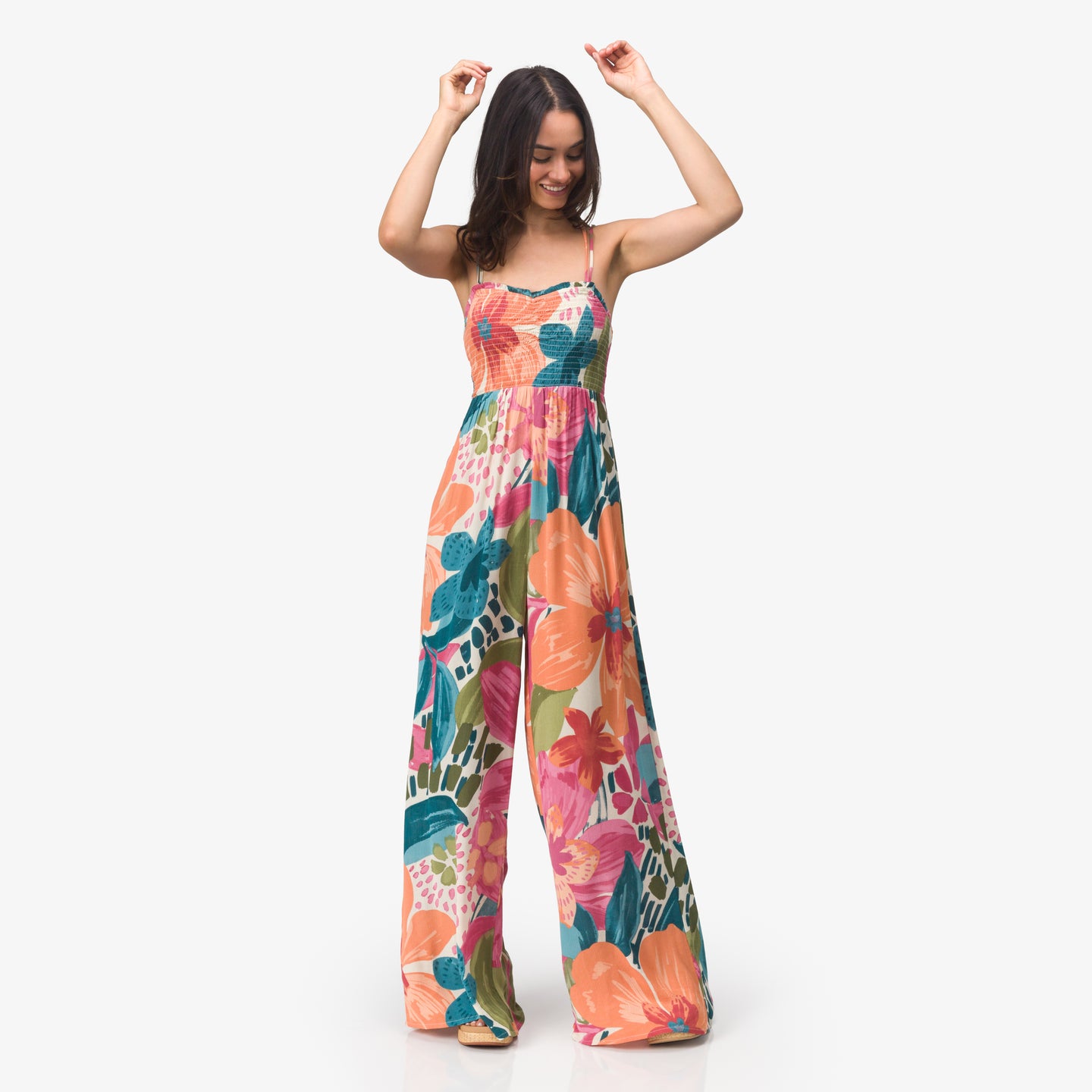 Woman wearing Eve Wide Leg Romper with colorful floral print, standing and smiling in a relaxed pose.