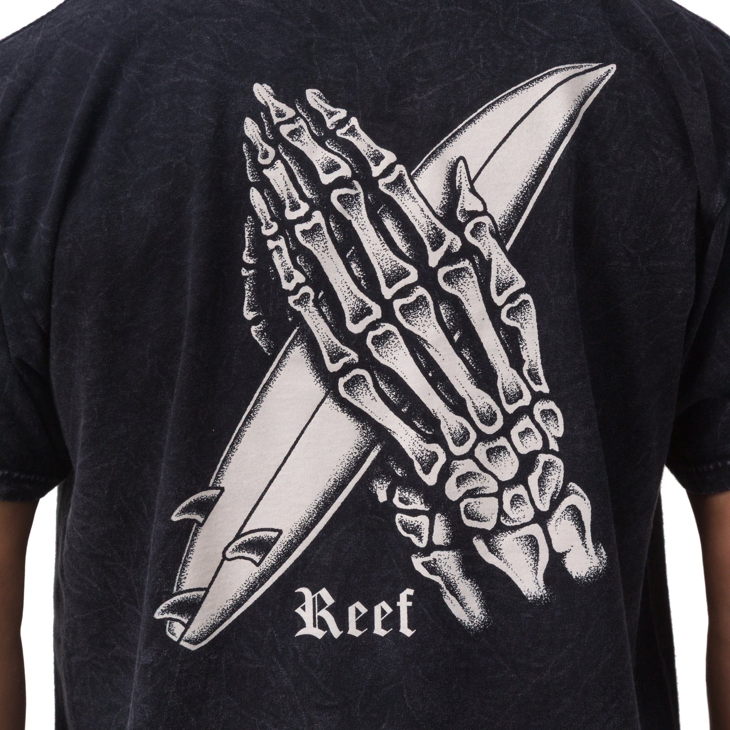 Close-up of the back of the Pray Tee showing a skeleton hand holding a surfboard print on black fabric.