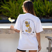 Woman wearing Social Boyfriend Crew t-shirt showing back graphic design, standing outdoors with drink in hand