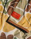 Close-up of Men's Bamboo Lightweight Hoodie - Floral Camo showing orange brand label, soft breathable fabric with earth tone camouflage design