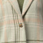 Close-up of the olive green and beige plaid Beverly Knit Trench showing textured fabric and button detail.