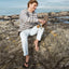 Man seated on rocks near beach wearing Fanning flip flops facing forward, showcasing comfort and water-friendly design.