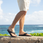 Side view of men's Cushion Phantom 2.0 flip flops on right foot by ocean, showing comfort and surf-inspired design.