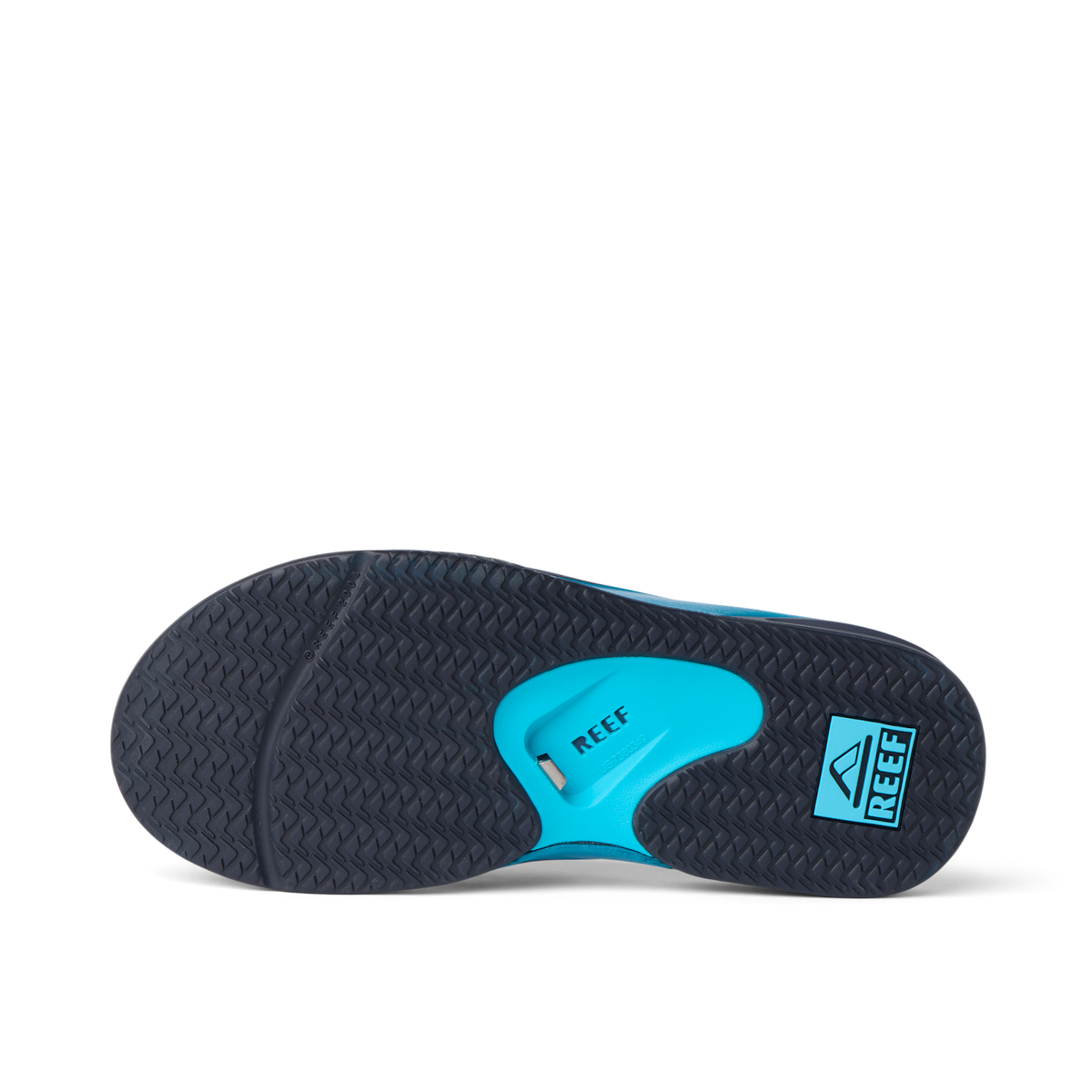 Fanning flip flop underside close up facing left, showing herringbone outsole, blue heel airbag, and REEF logo