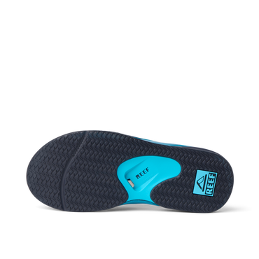 Fanning flip flop underside close up facing left, showing herringbone outsole, blue heel airbag, and REEF logo