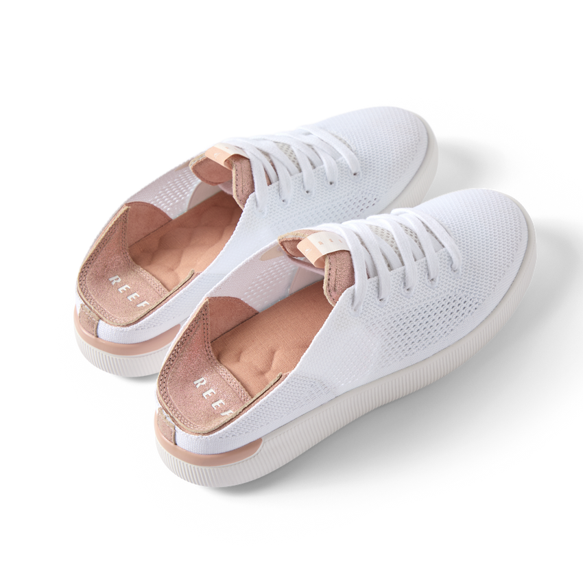 Reef Neptune women's white and rose gold sneakers angled side view showing lightweight knit upper and cushioned heel.