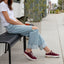 Reef Del Mar burgundy sneakers facing right on a woman seated outdoors