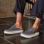 Rambler Kicker slippers facing right worn indoors, featuring cushioned memory foam footbed and lightweight EVA outsole in charcoal gray