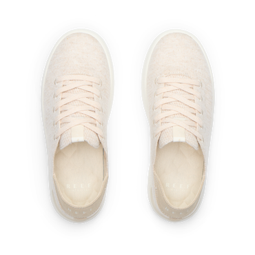 Pair of cream lace-up sneakers viewed from above, both facing upward with toes away and heels toward the viewer