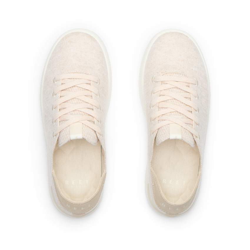 Pair of cream lace-up sneakers viewed from above, both facing upward with toes away and heels toward the viewer