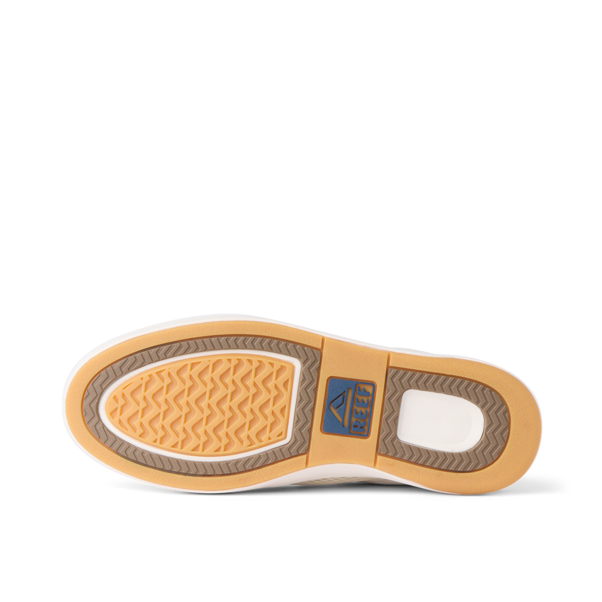 Bottom sole of a REEF shoe facing upward showing tread pattern and logo in tan, brown, and white colors.