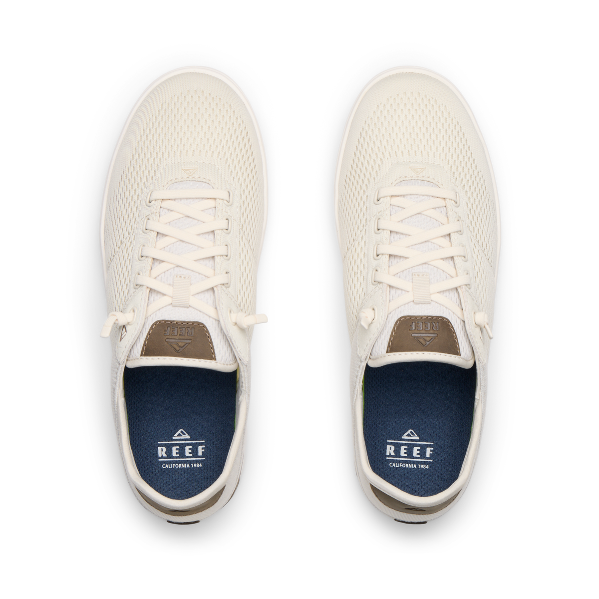 Top view of pair of cream-colored REEF sneakers facing upward with mesh uppers and blue cushioned insoles.