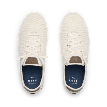 Top view of pair of cream-colored REEF sneakers facing upward with mesh uppers and blue cushioned insoles.