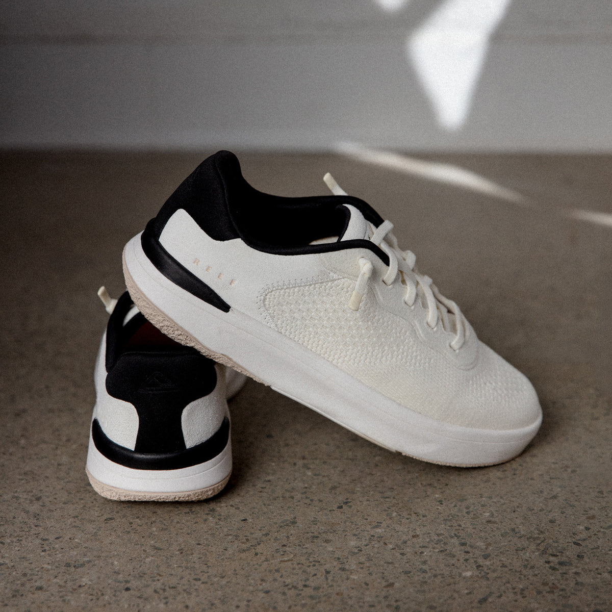 Reef Del Mar white sneakers, one facing right and another showing the heel, with lightweight cushioned comfort