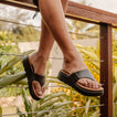 Cali Laguna black platform sandals with toes facing right and cushioned footbeds in a tropical lifestyle setting