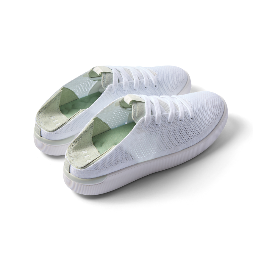 Pair of Reef Neptune shoes facing right, featuring white and dusty sage colors, knit material, and cushioned arch support.