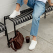 Reef Del Mar white sneakers facing forward on a person seated on a bench with cushioned everyday comfort