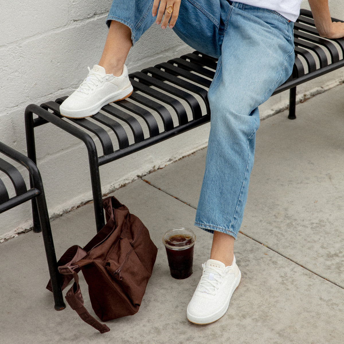 Reef Del Mar white sneakers facing forward on a person seated on a bench with cushioned everyday comfort