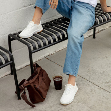 Reef Del Mar white sneakers facing forward on a person seated on a bench with cushioned everyday comfort